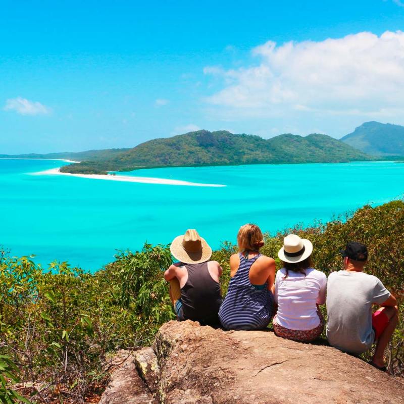 a person sitting on a rock next to a body of water