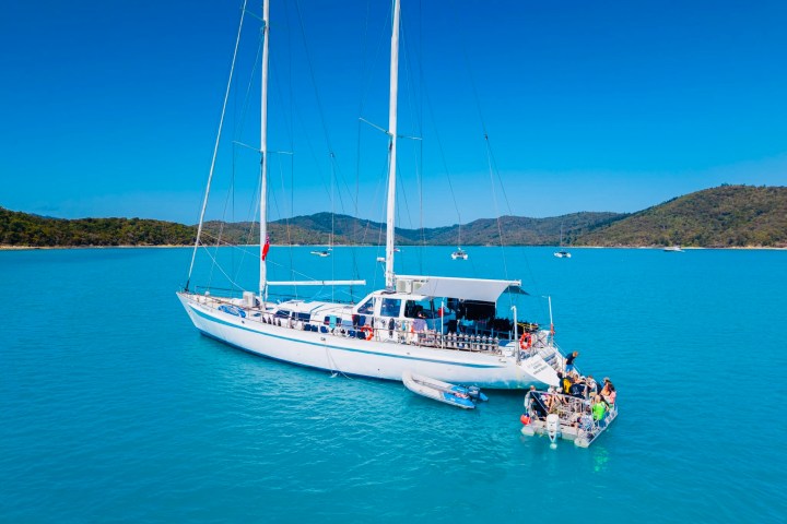 Summer Jo anchored on turquoise water with people on a small raft.