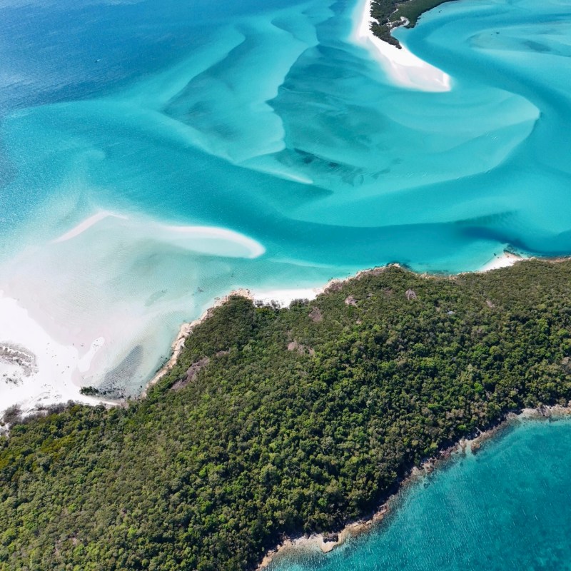Aerial view of turquoise ocean meeting lush green coastline.